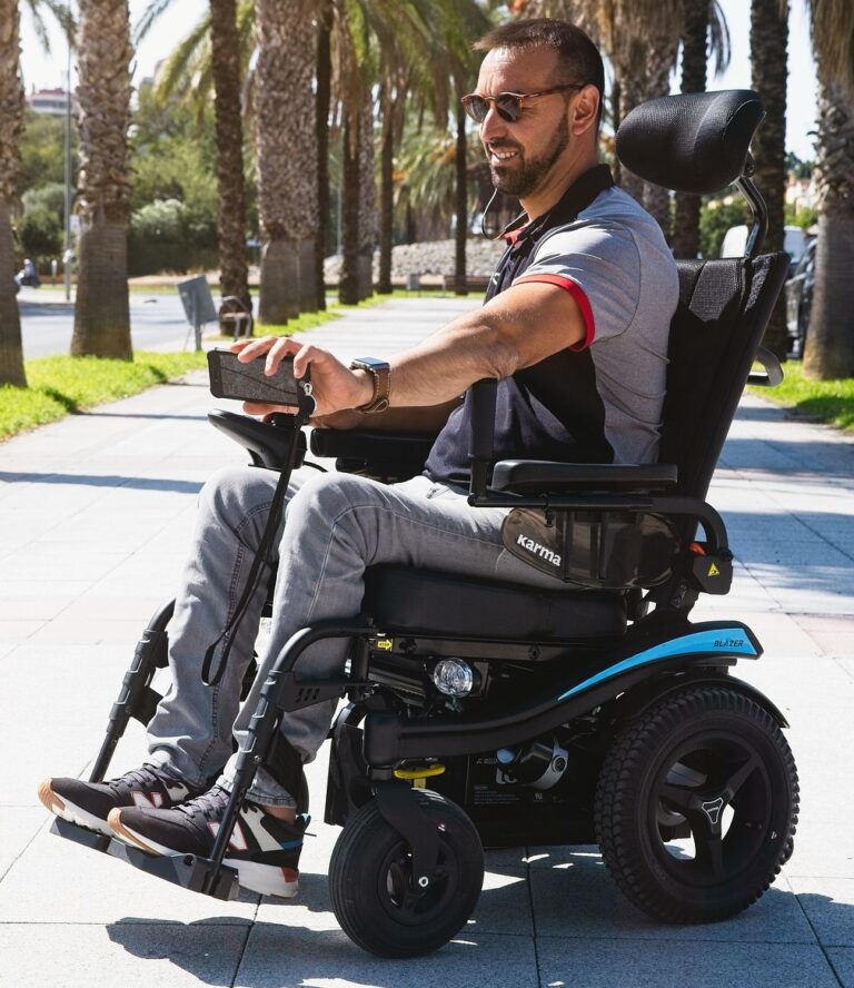 Man in motorized wheelchair in park with cell phone